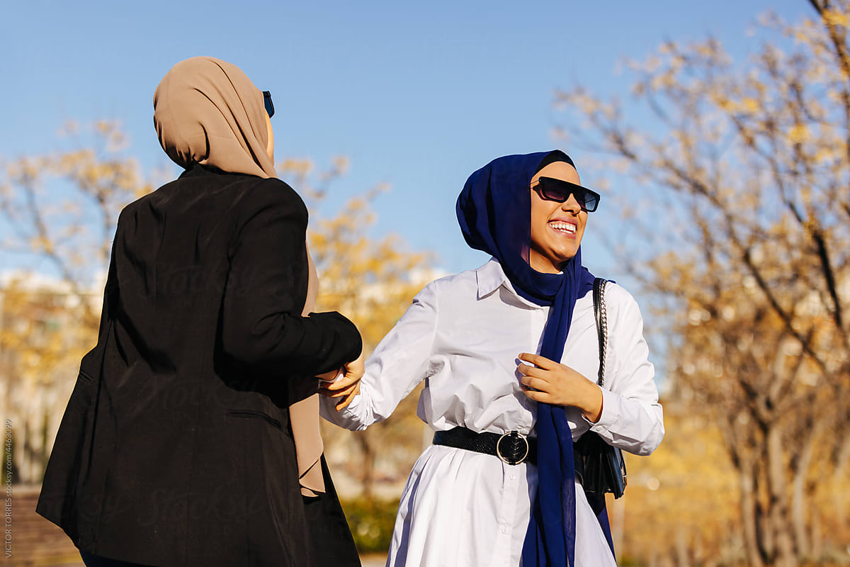 Cheerful Muslim Women In Trendy Clothes And Sunglasses by Stocksy  Contributor VICTOR TORRES - Stocksy