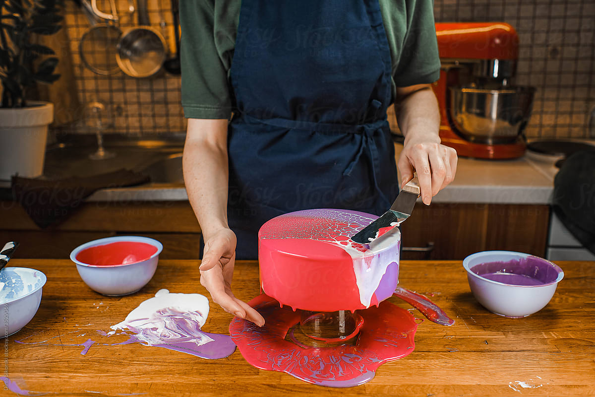 a pastry chef decorates an unusual mousse cake with icing at home