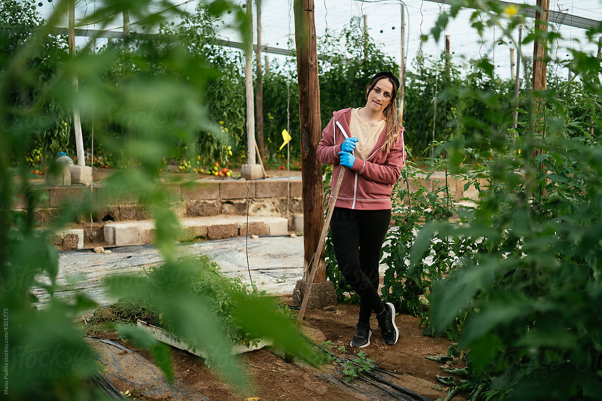 Woman leaning on tool in greenhouse