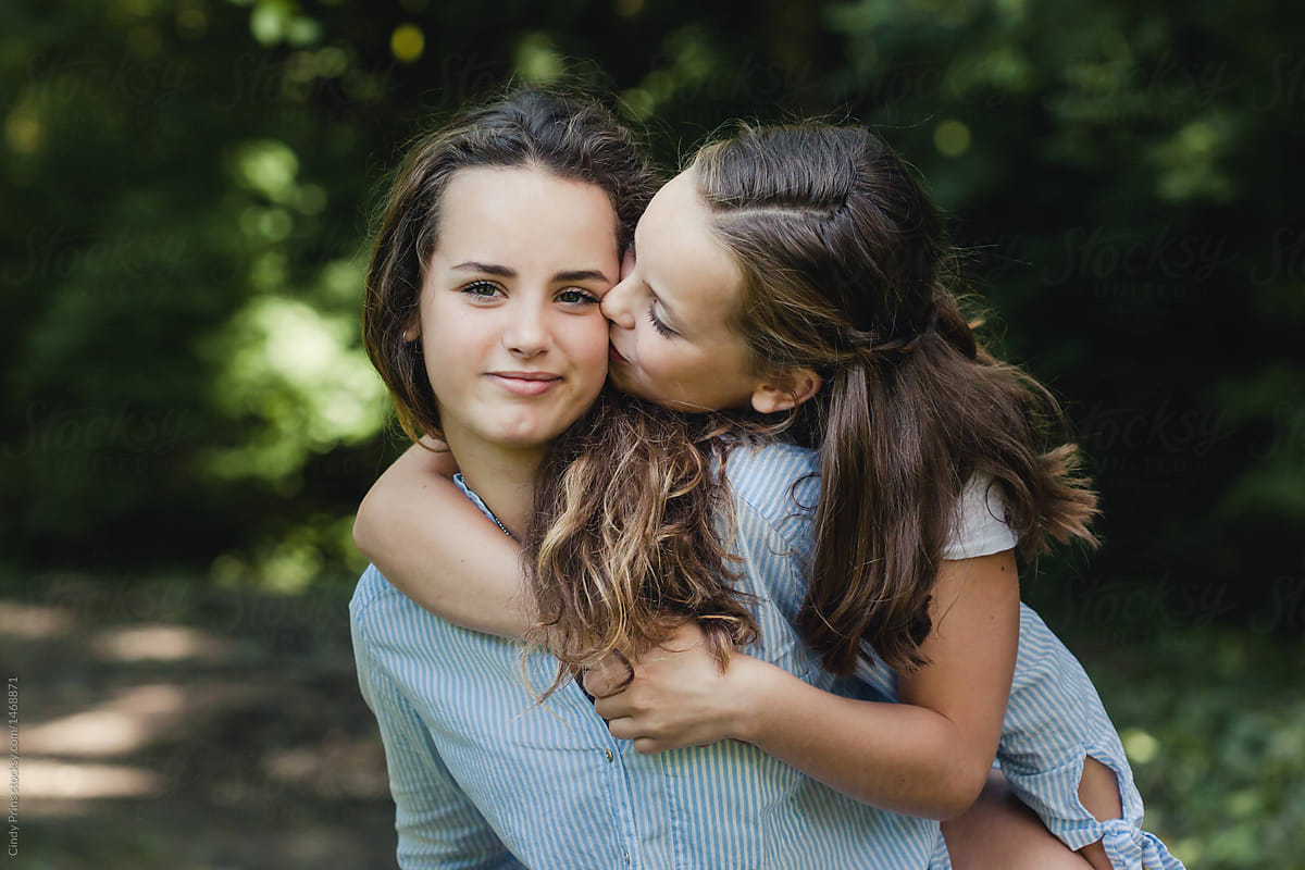 Sweet portrait of little girl giving her big sister a kiss by Cindy Prins f...