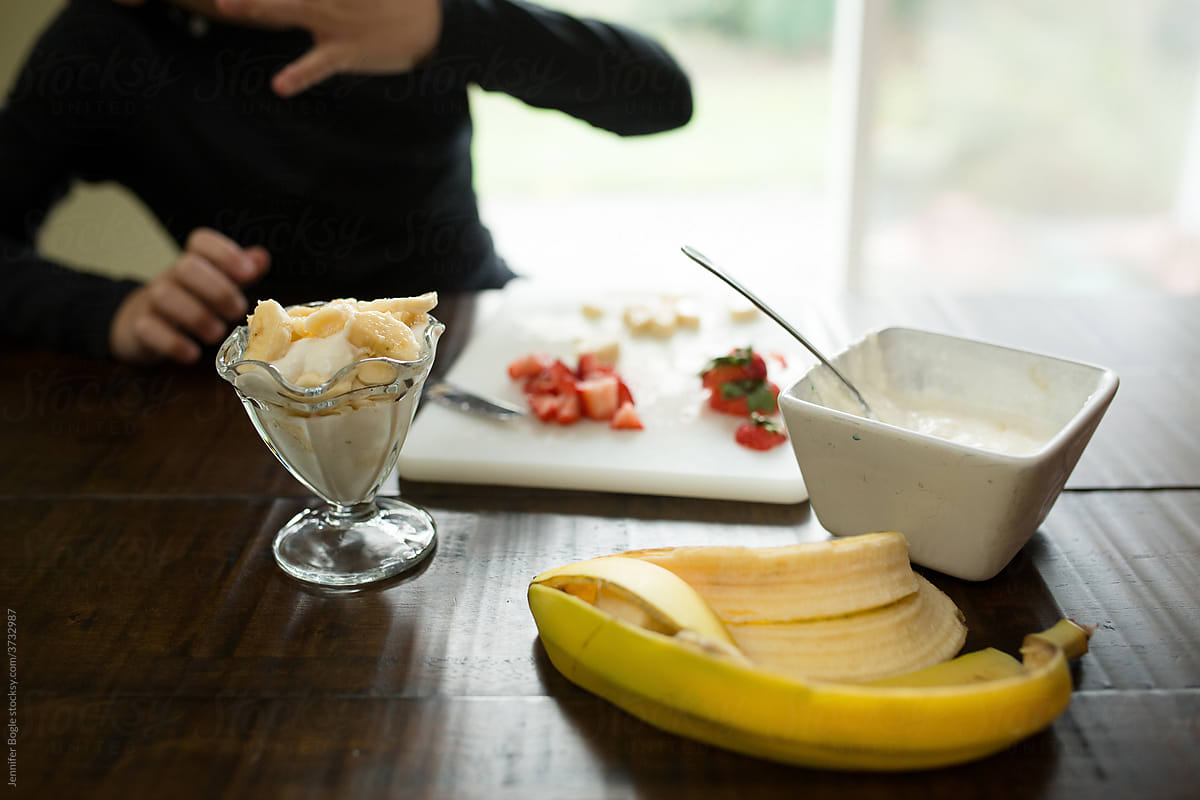 Child preparing banana strawberry yogurt