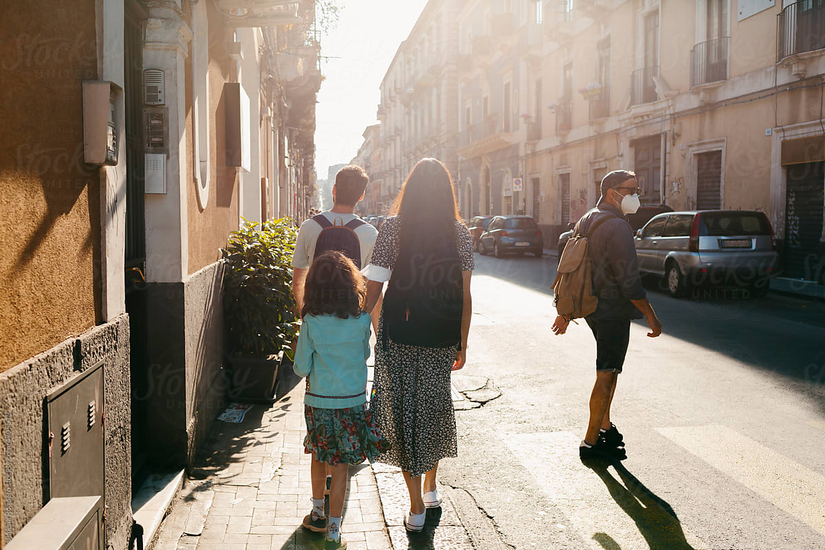 Family walking on old italian city street in sunlight