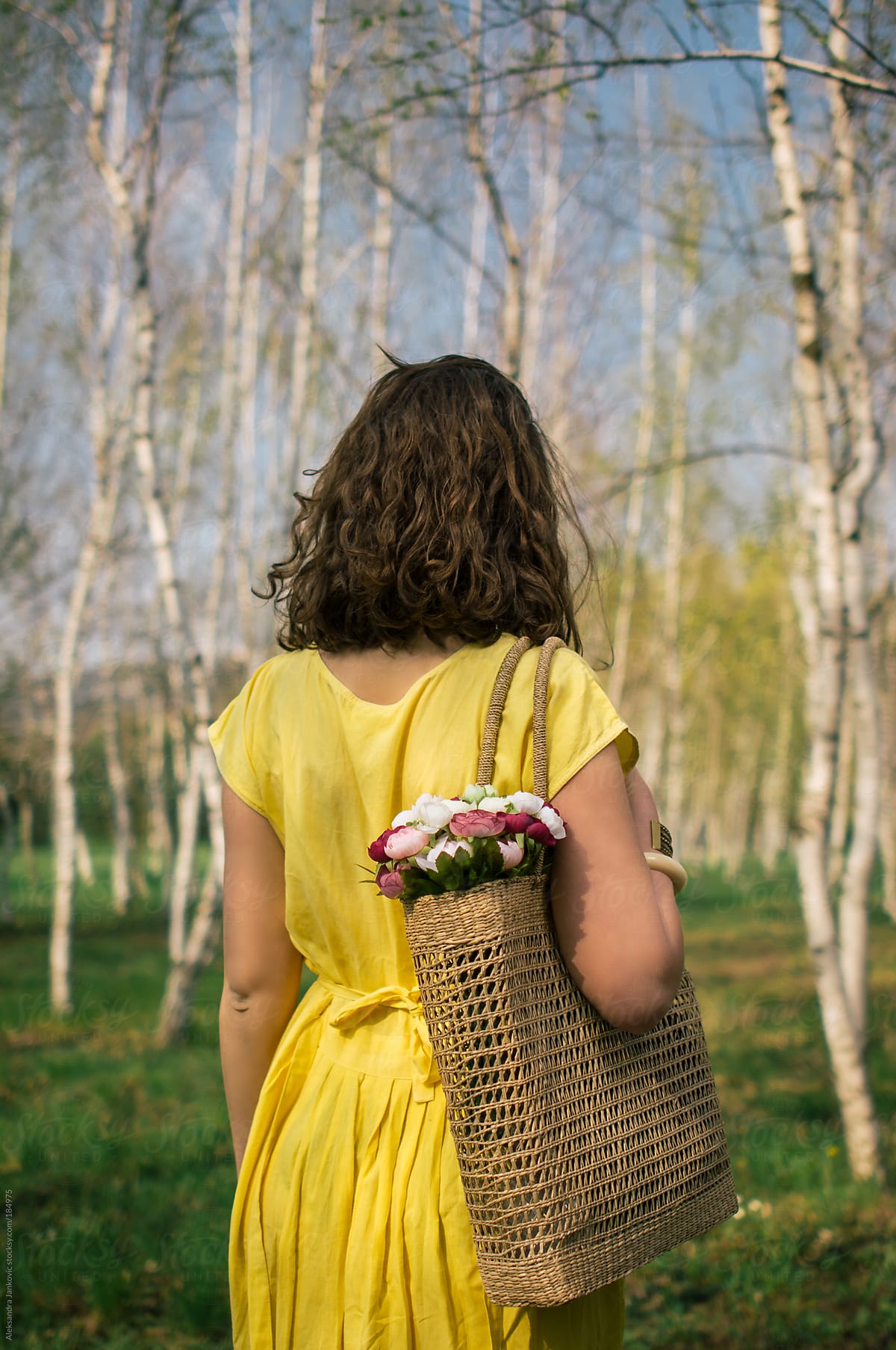 Anonymous Woman In Yellow Dress Holding A Bag With Flowers