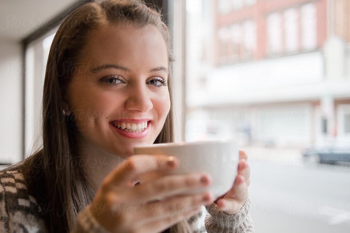 Young woman across the table enjoying latte in a cafe