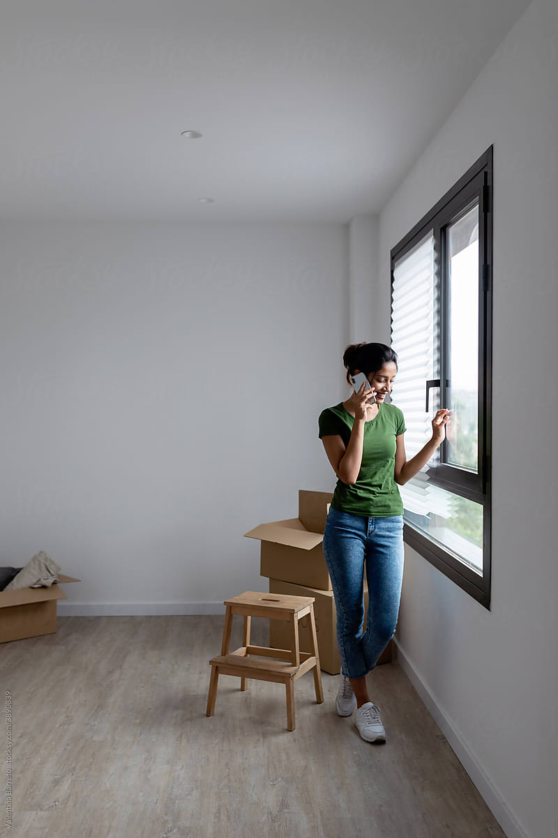 Young woman talking by phone at new apartment