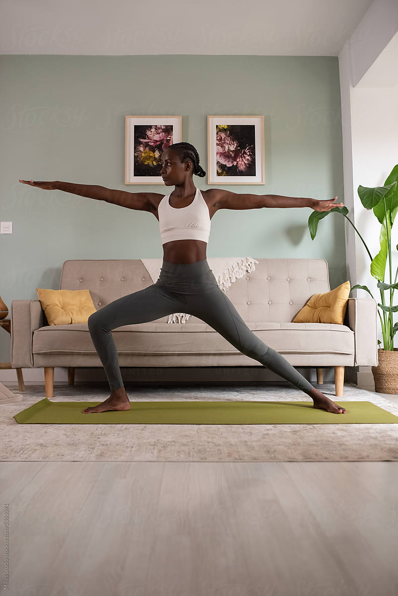 Woman practicing yoga in Warrior II pose at home