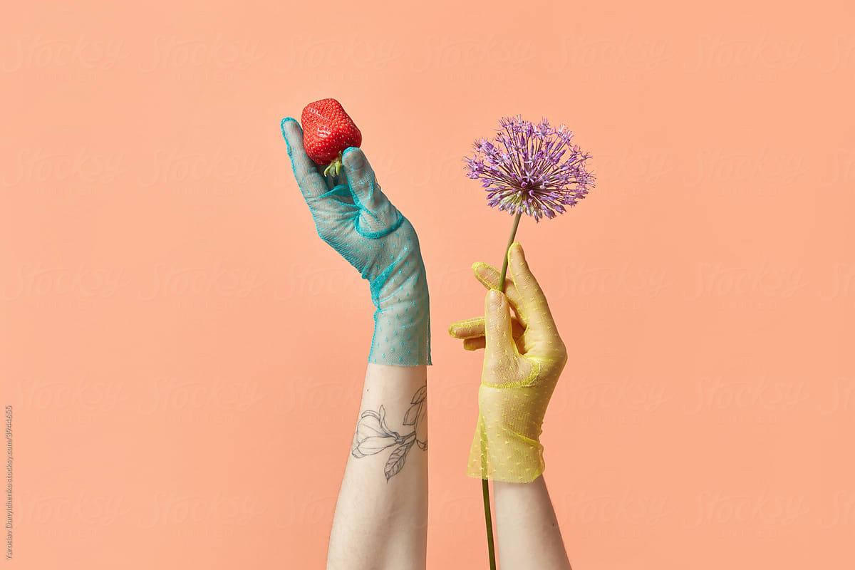 Woman in gloves holding strawberry and flower