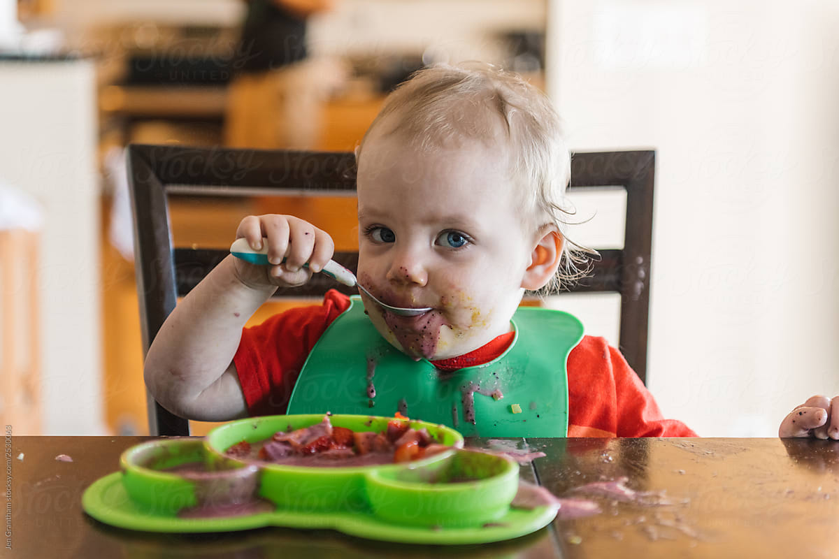 Messy toddler eating a smoothie bowl
