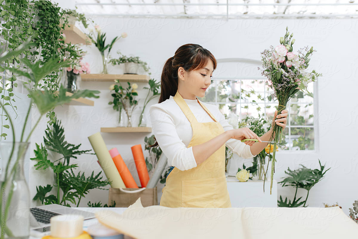 Woman florist making flower composition at florist workshop.