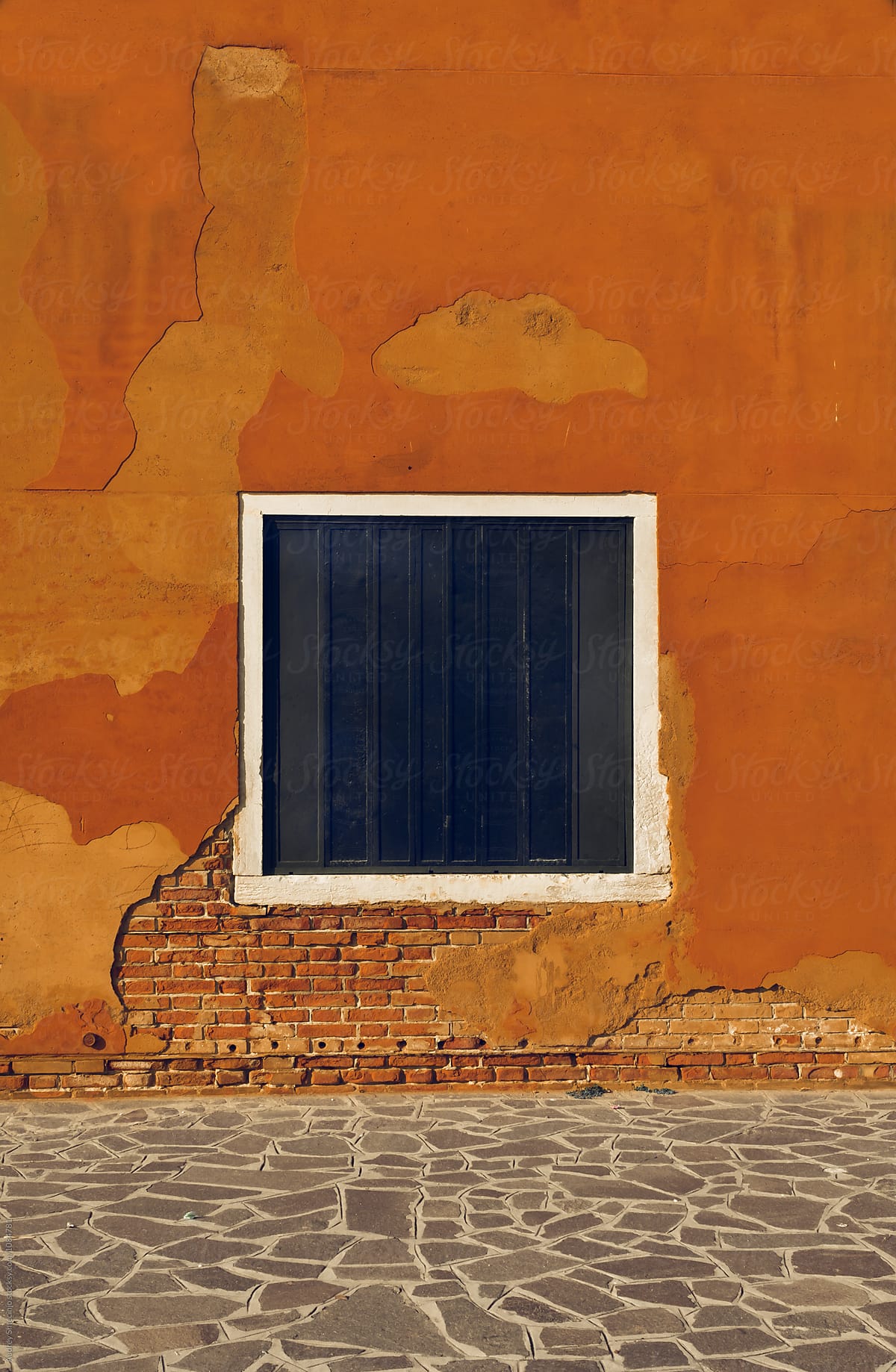 Mediterranean house detail/blue square window/opening on rustic orange wall.Venice/Italy