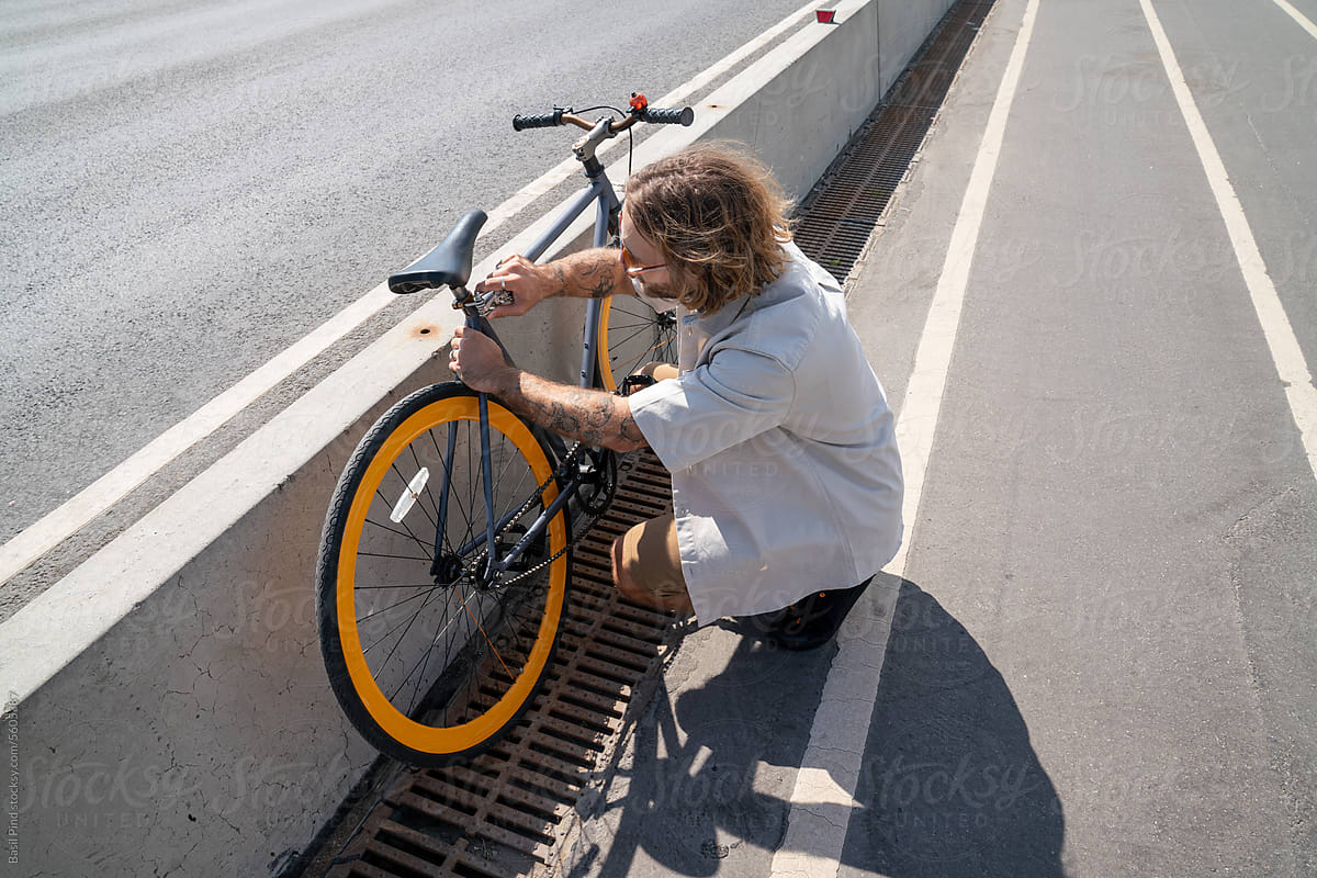 man with long blonde hair fixing bike