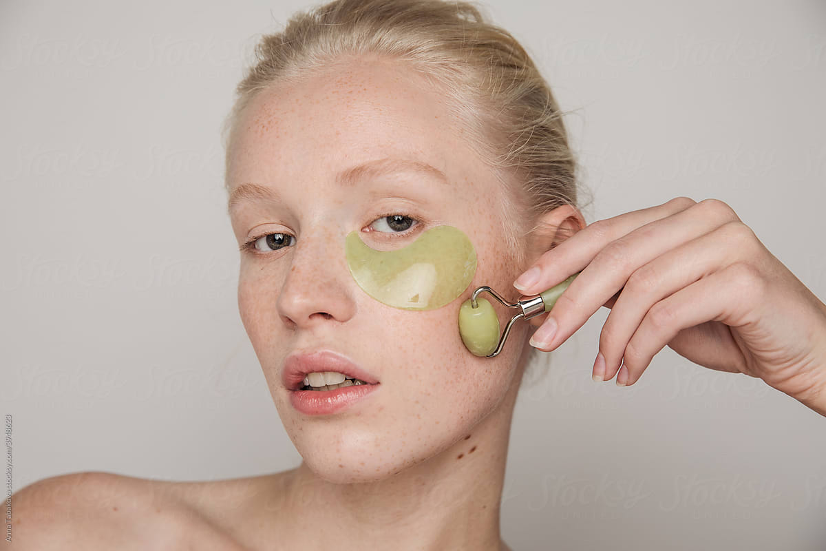 Model with green jade roller and under-eye patch