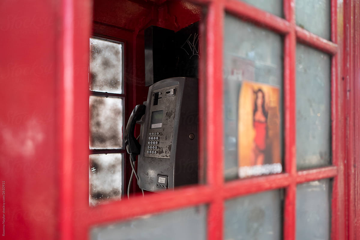London public phone box with blurred escort services sticker