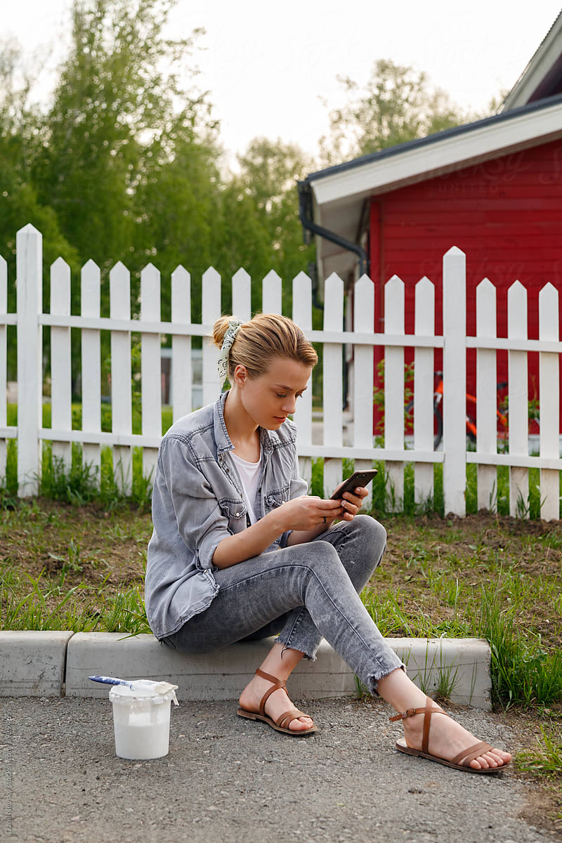 Female painter using smartphone near fence