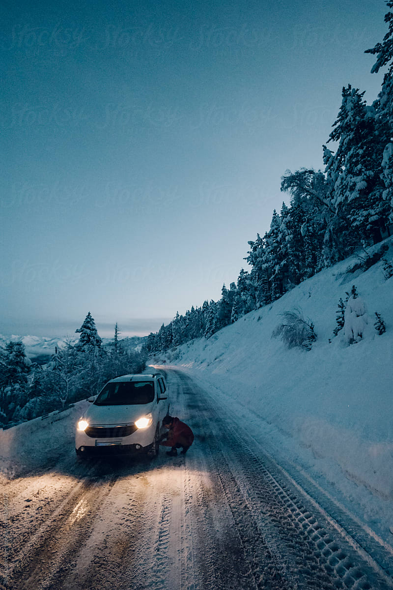 Man outside his car in the snowy road at sunrise moment