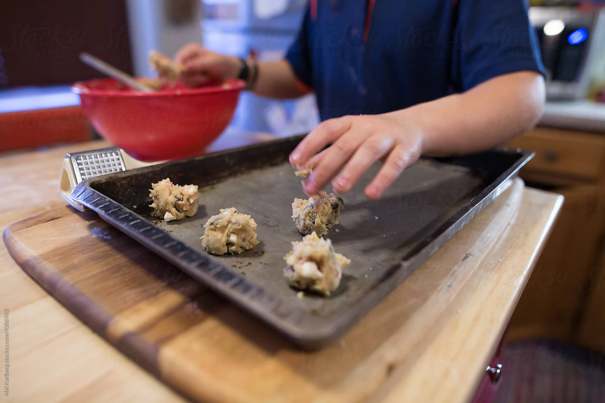 Kids hand placing cookies on pan