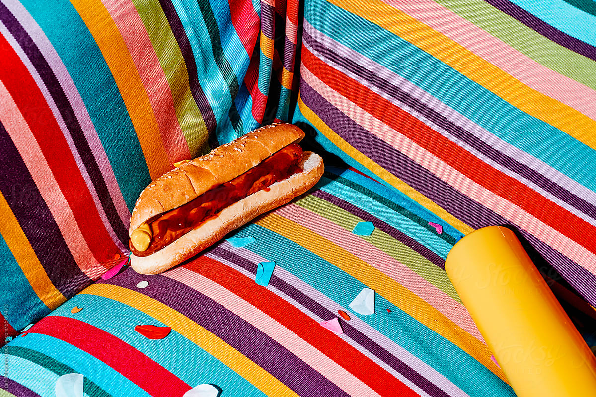 hotdog and squeeze bottle with mustard on a chair