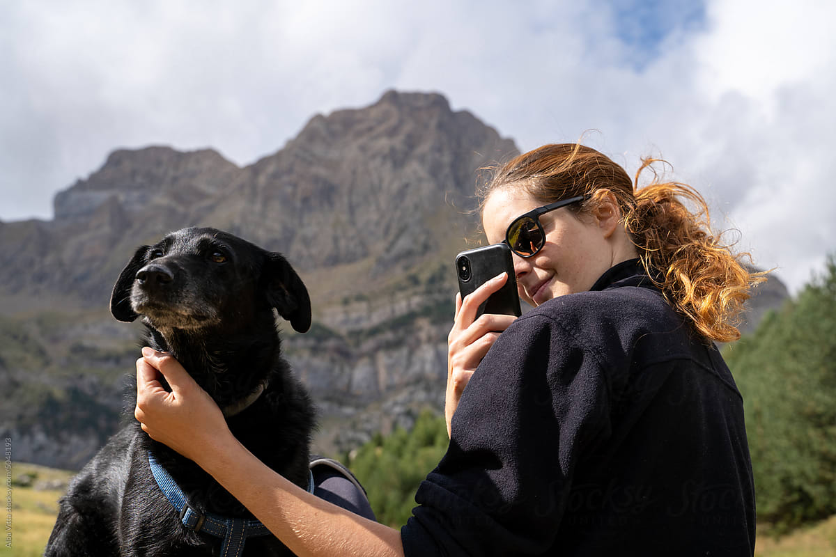 Hiker woman in the mountain with dog and phone