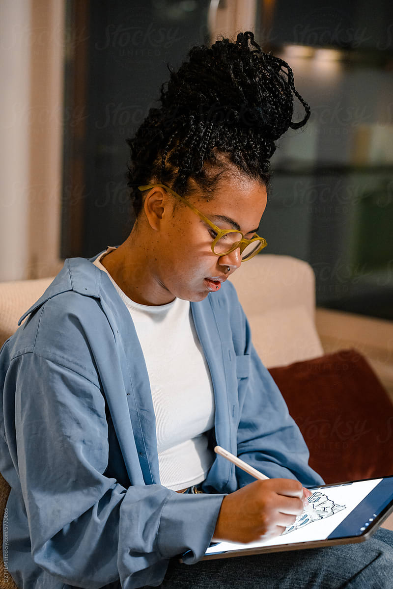 A woman draws on a tablet at home