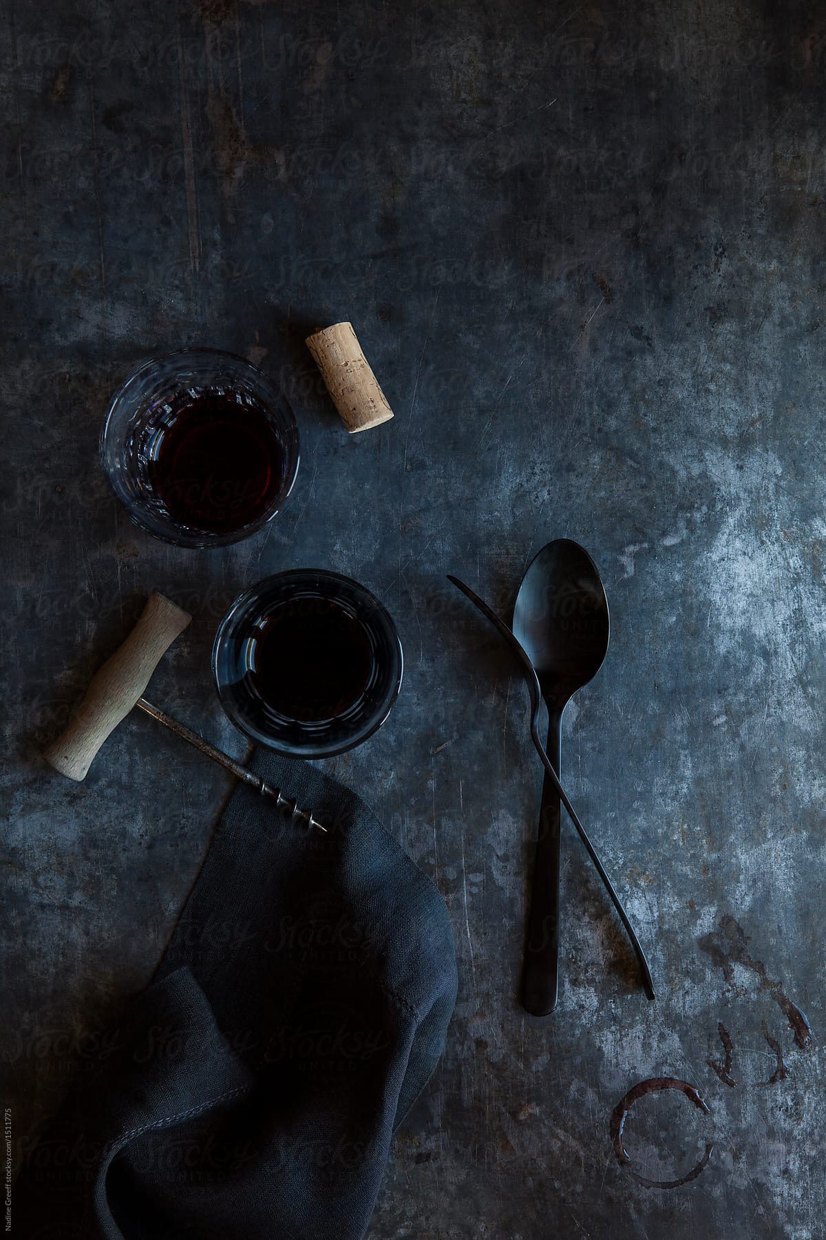Black cutlery and two glasses of red wine on a table