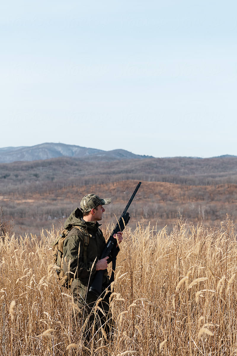 Adult huntsman in field near mountains