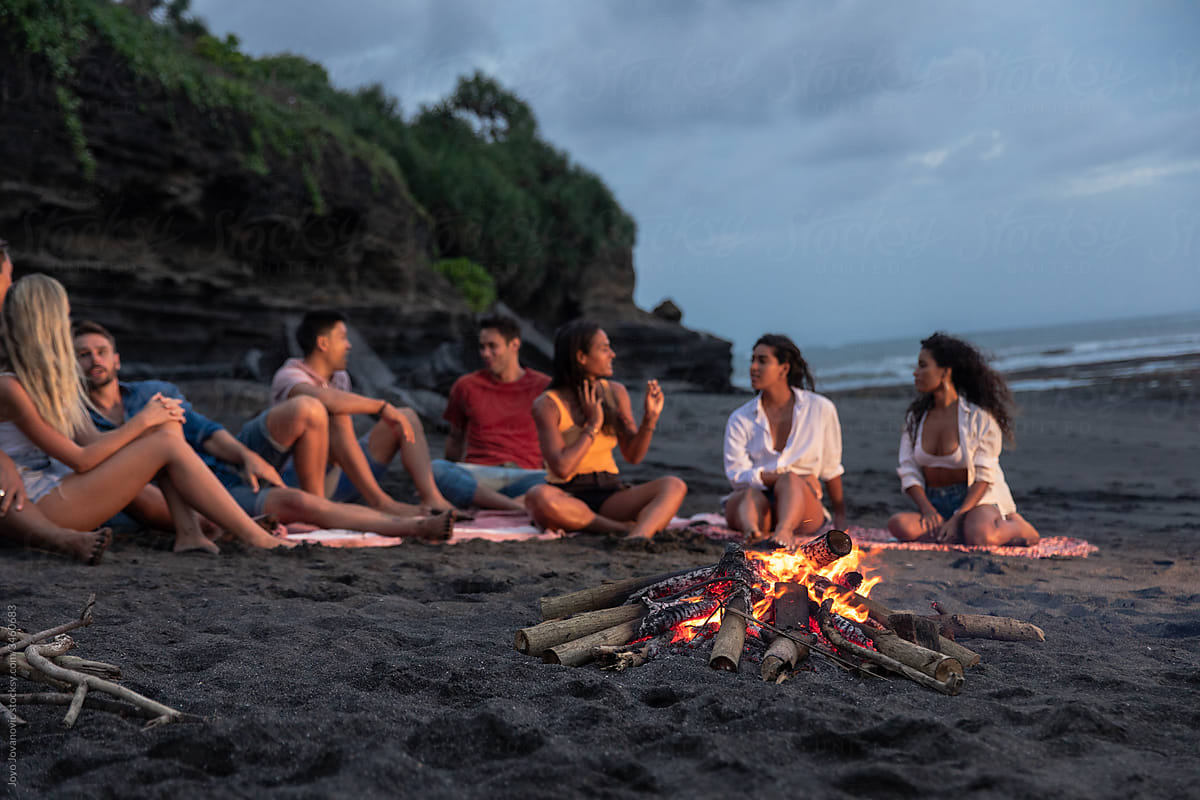 Multi-Ethnic Group of friends talking around bonfire at summer evening