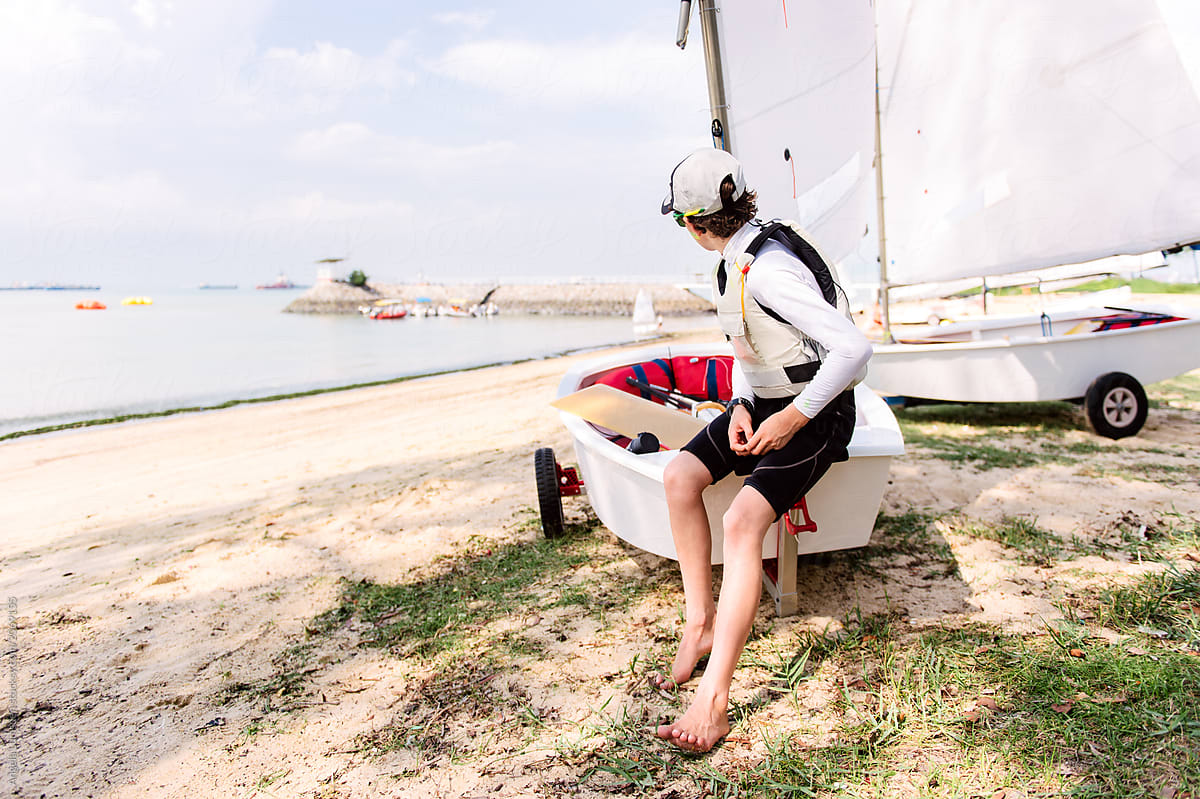 Teenage boy sitting on the side of an optimist dinghy