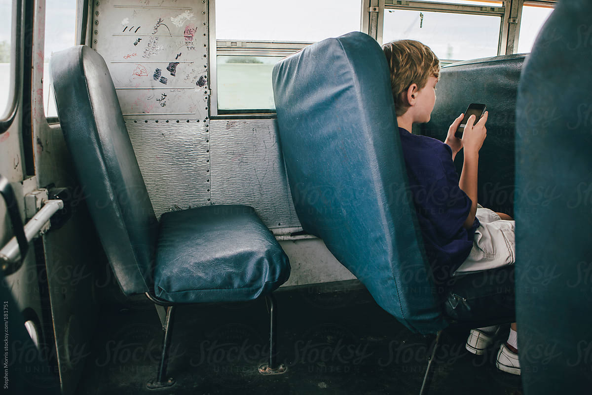 Boy on school bus using smart phone