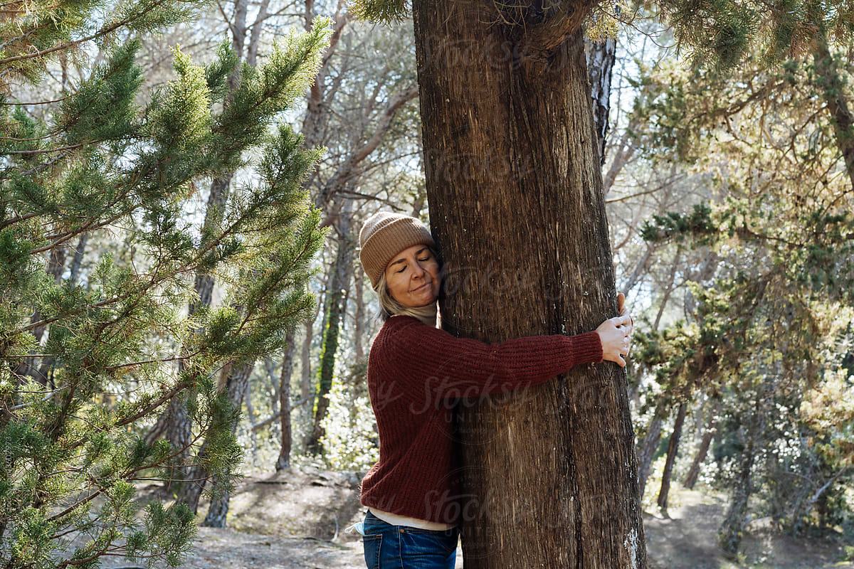 Middle aged woman hugging tree trunk