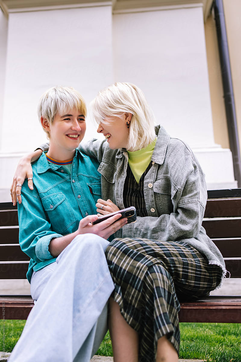 Lesbian couple laughing with something on phone