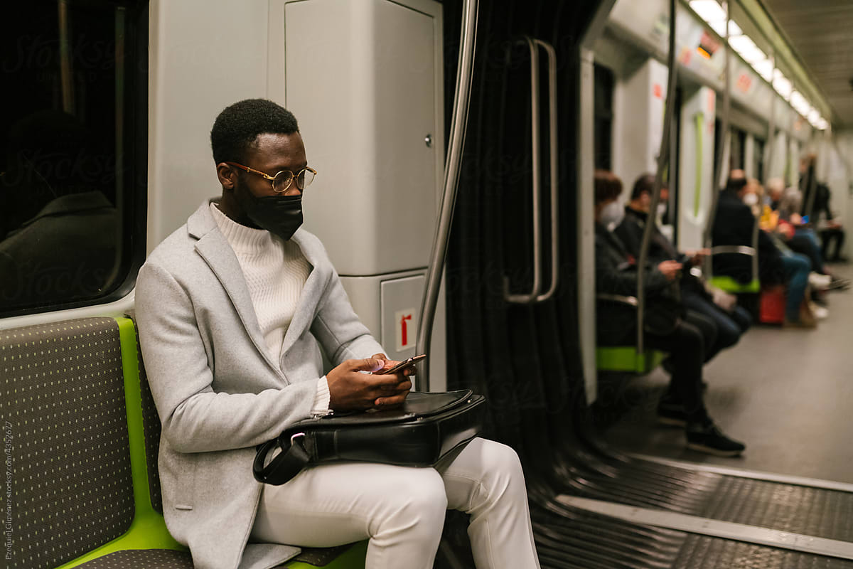 Black man browsing smartphone in metro