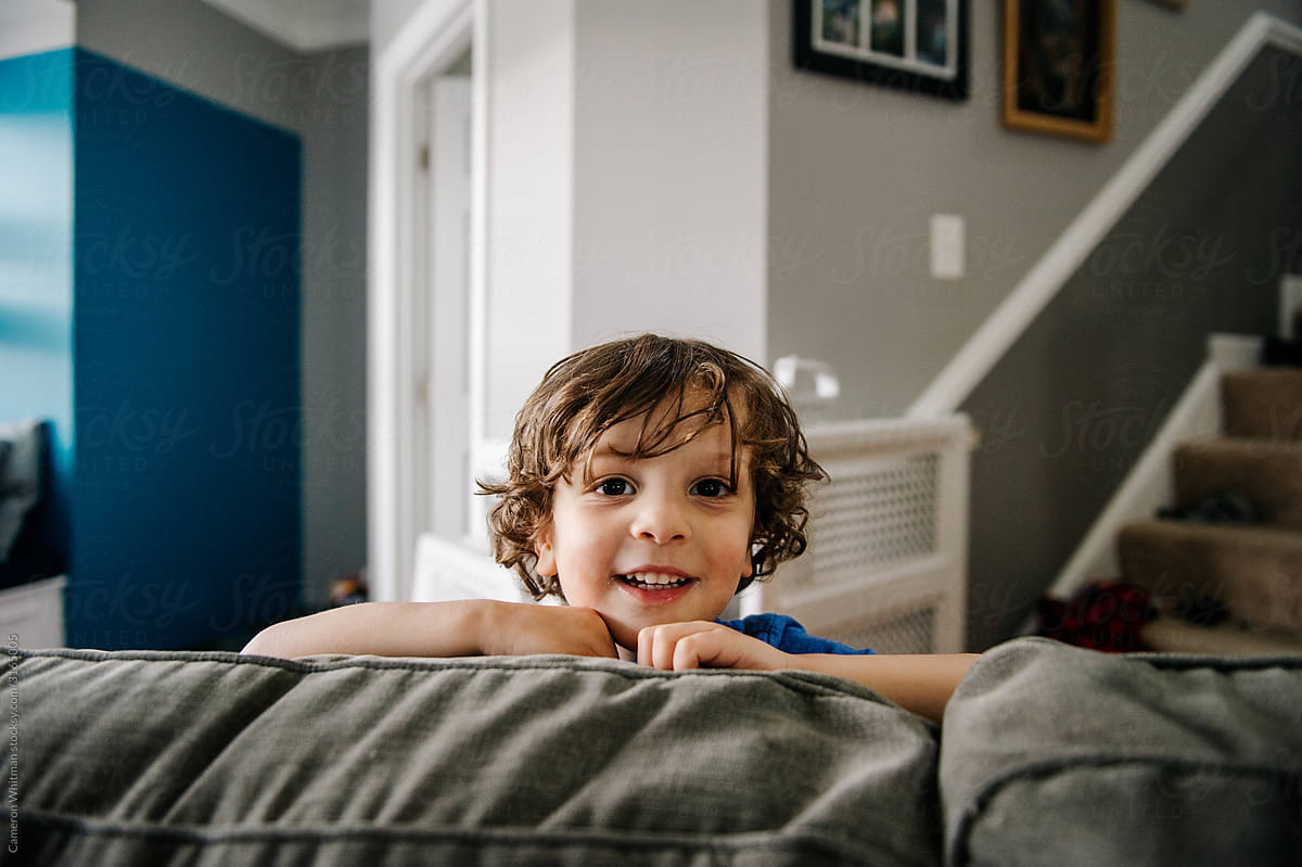 Preschooler boy pops up with a surprise visit behind the couch