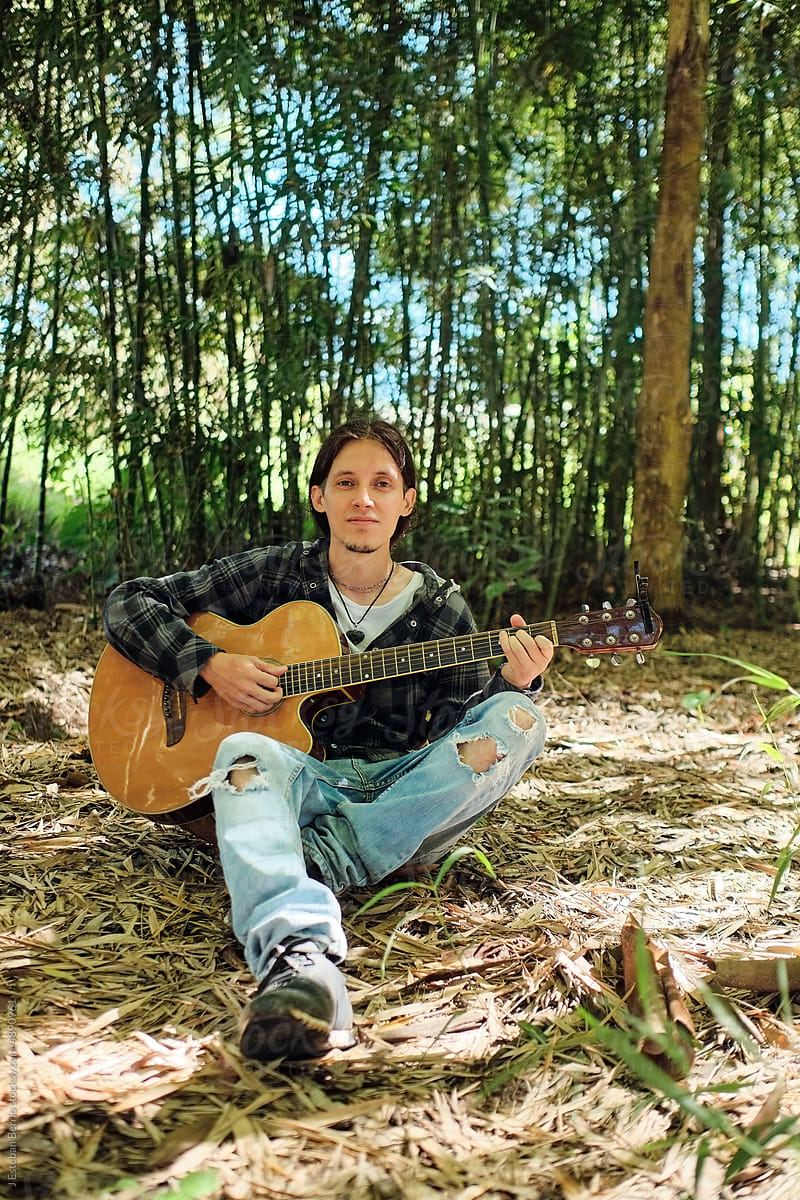 Portrait of guitarist sitting on dry leaves