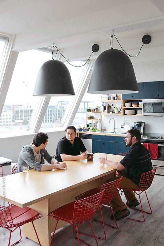 Three men meeting at kitchen table in office environment
