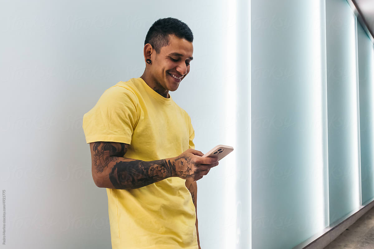Young tattooed latin man using smartphone in the city
