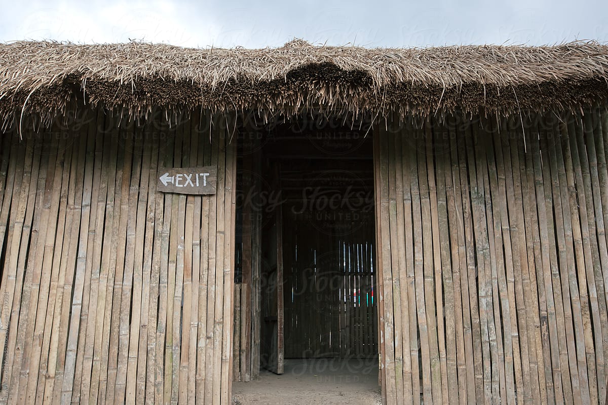 Exit sign by the door of a tropical hut made of thatched dry leaves and bamboo.