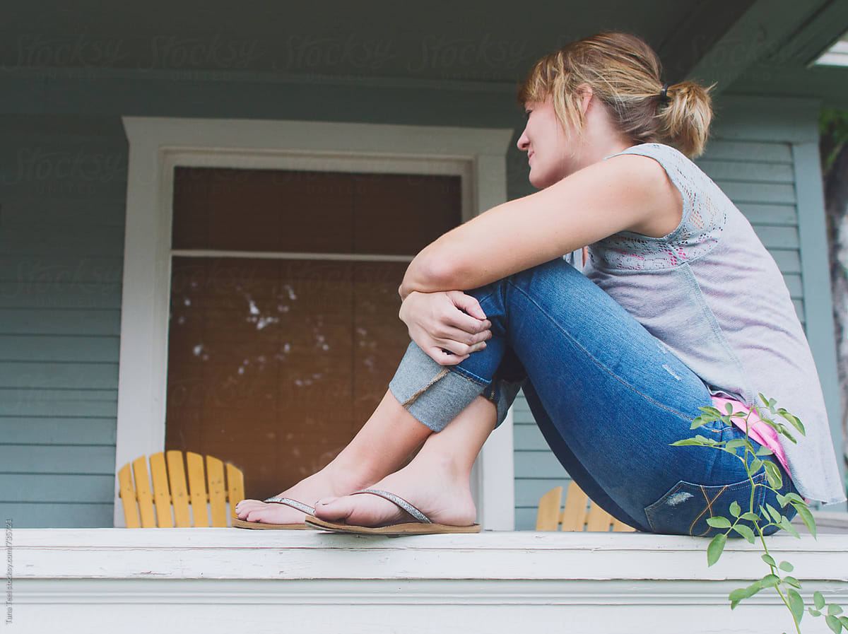 Woman sitting crossed leg on porch rail