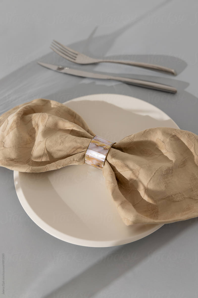 Cotton napkin with the ring, white plate, and cutlery on the table