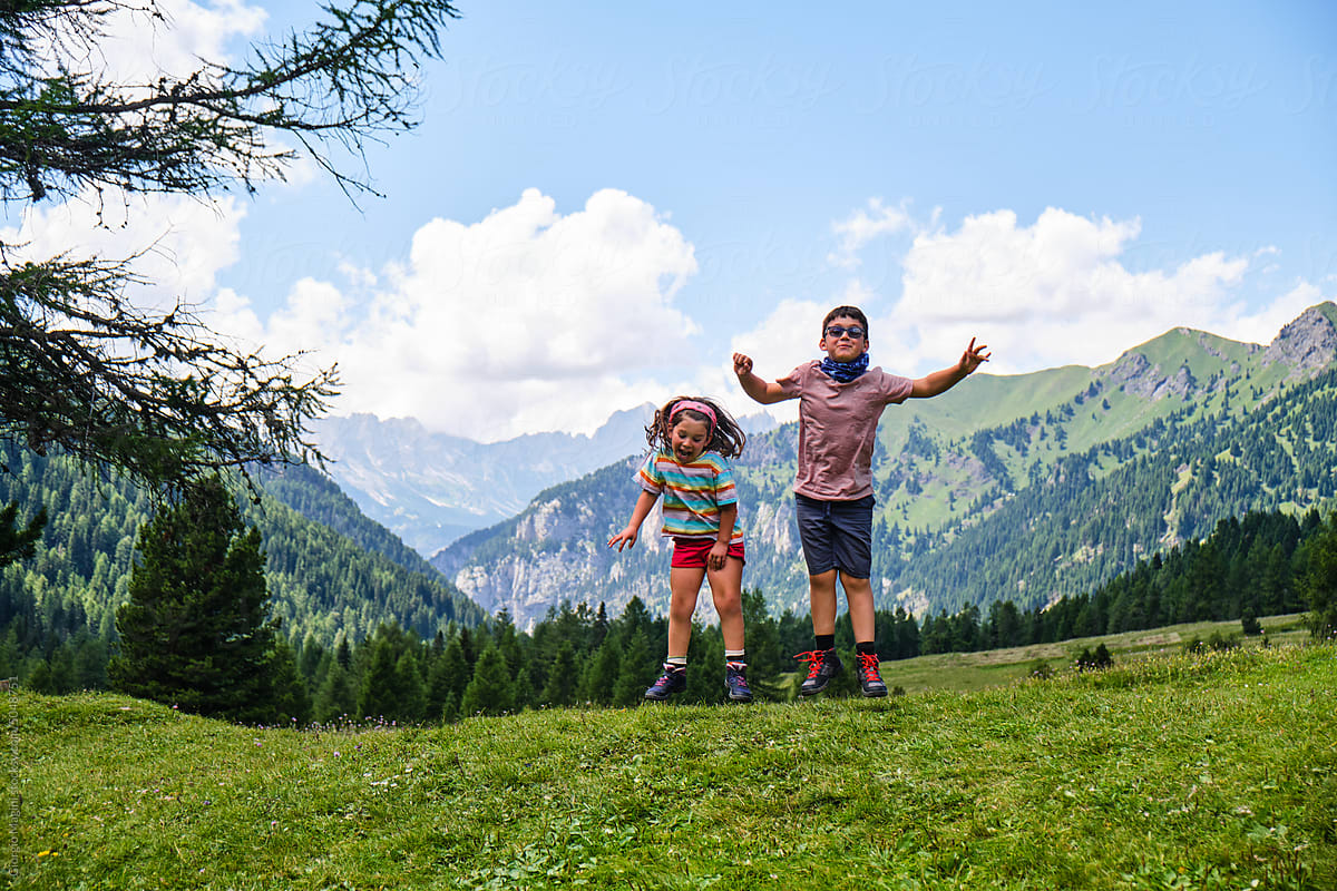 Little Siblings Jumping on the Grass during a Mountain Trip
