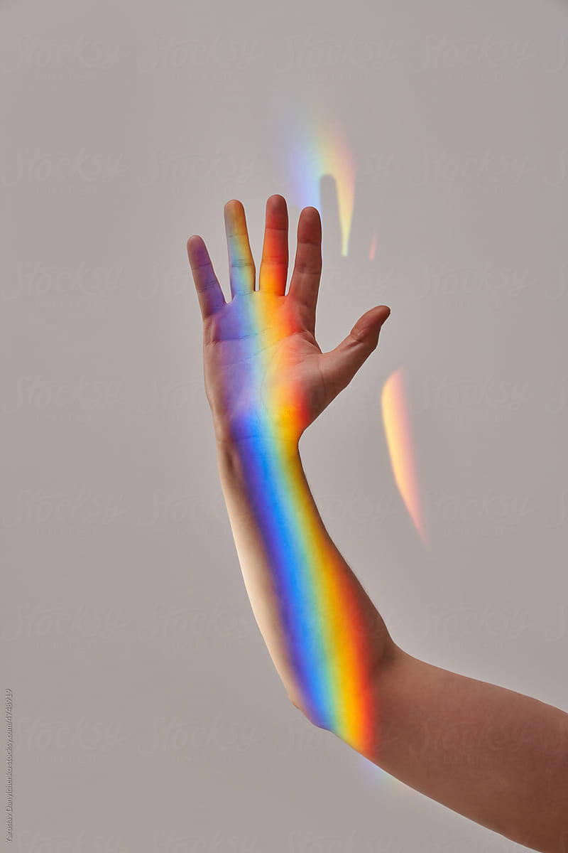 Person\'s hand with rainbow on skin.
