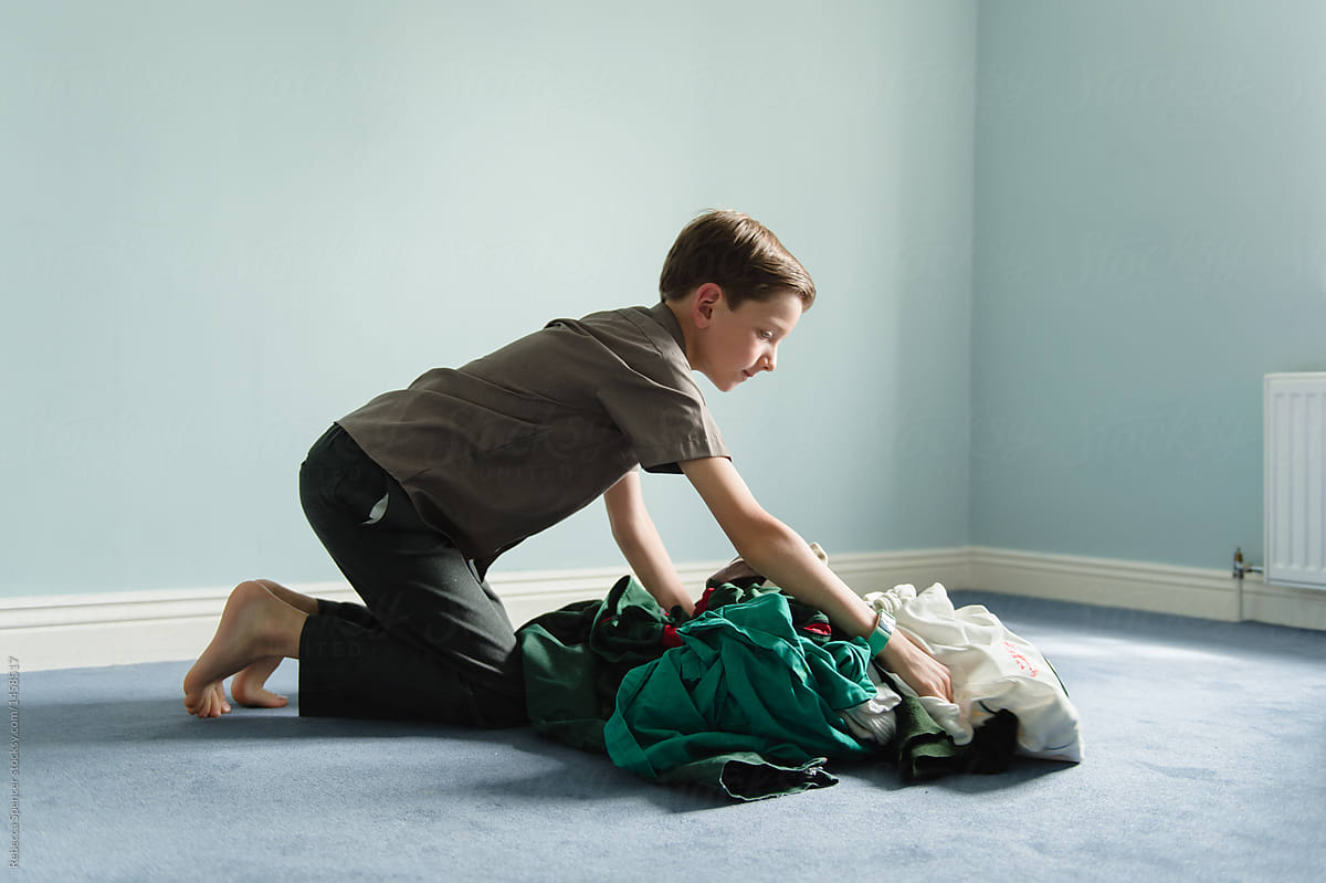 Boy Picking Up Dirty Laundry Off The Floor porRebecca Spencer