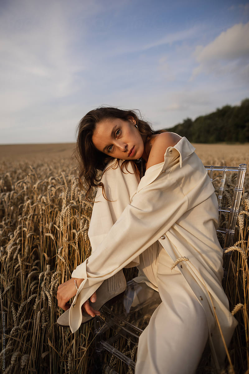 Female model posing on seat among wheat