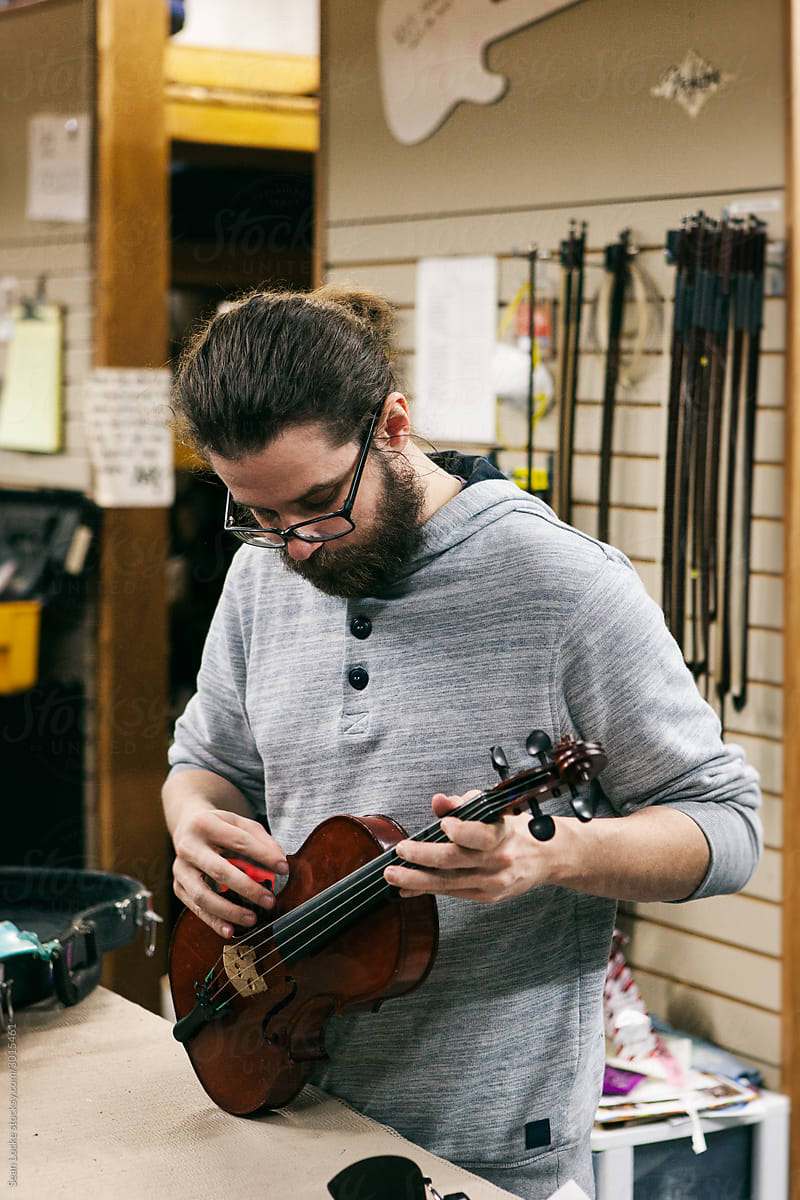 Band: Man Tuning Violin And Testing Strings