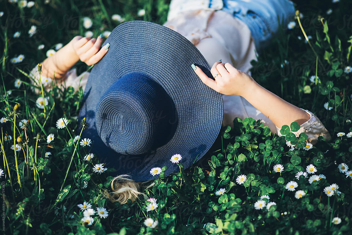Beautiful Young Woman Lying On Grass Wearing A Summer Hat Del Colaborador De Stocksy Jovana