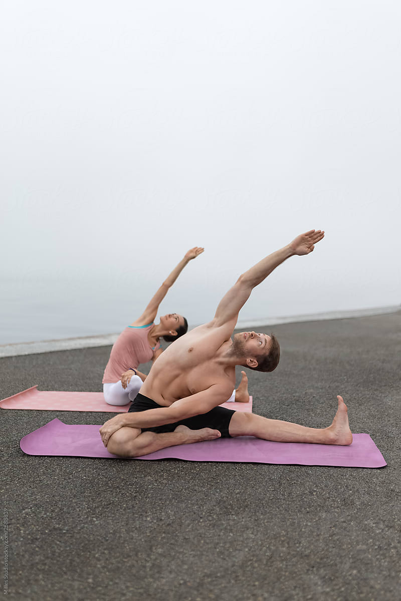 Stretching fit couple training yoga on shore