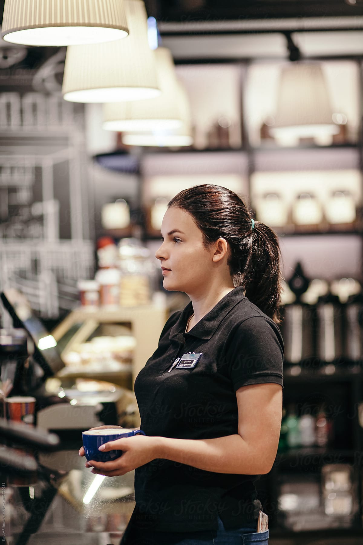 Woman barista holding cup of latte