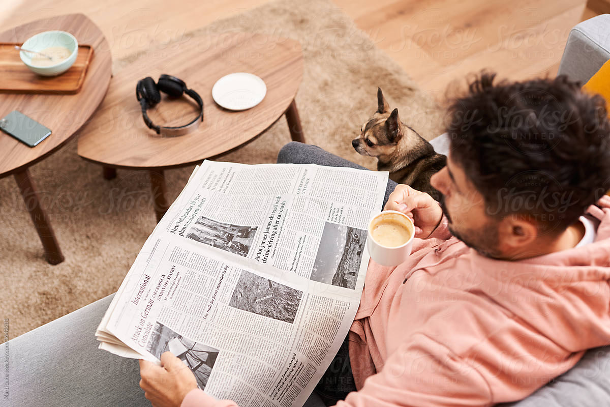 Man with dog reading newspaper during breakfast in living room