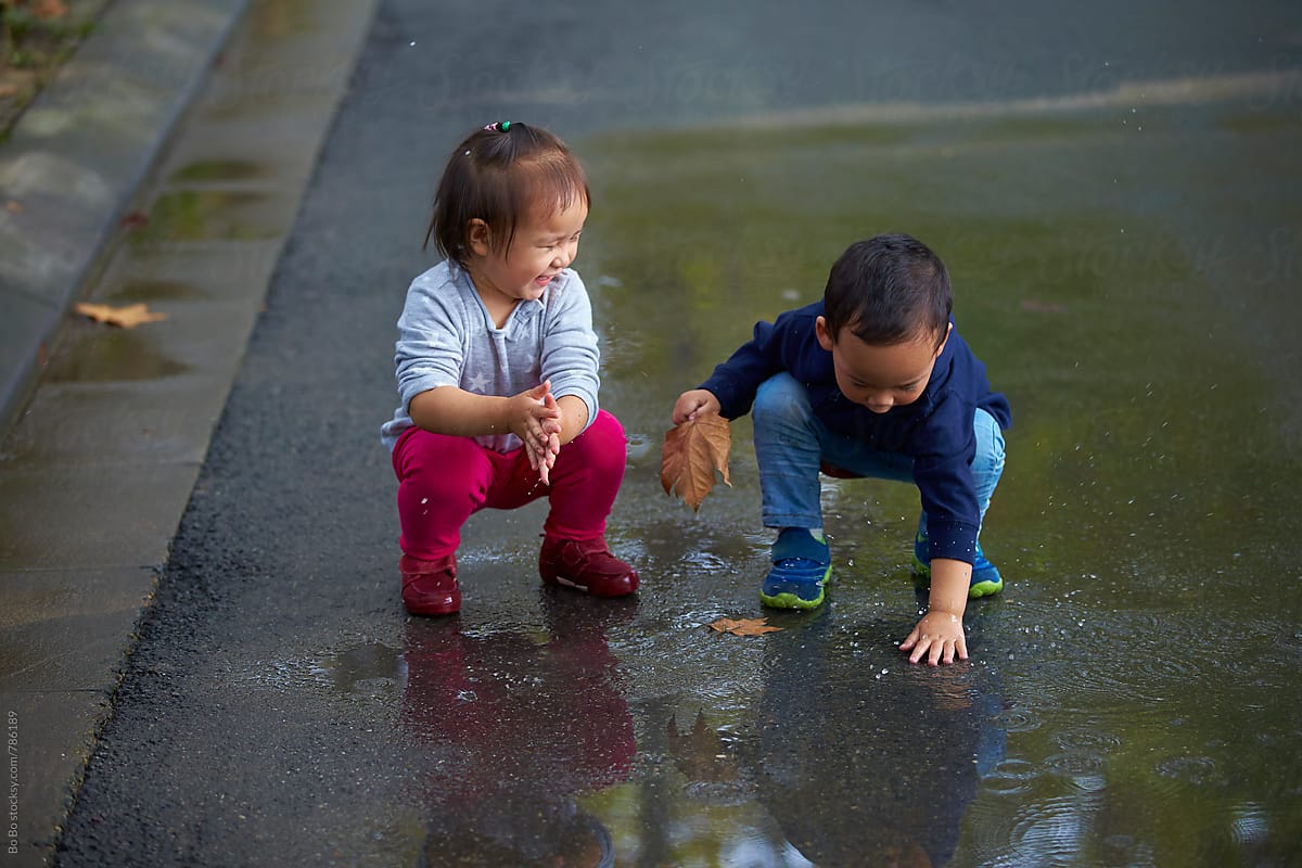 two lovely little kids playing on wet road