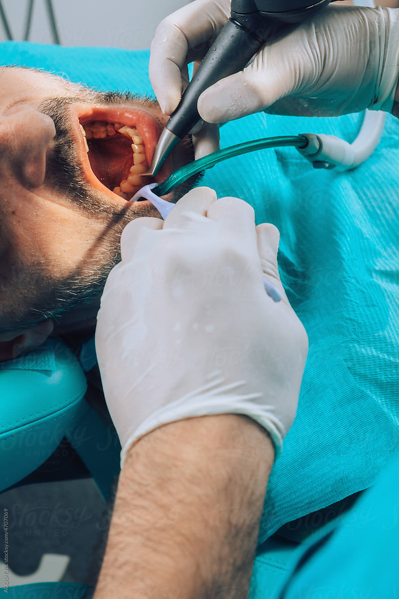 Dentist using various instruments on patient teeth