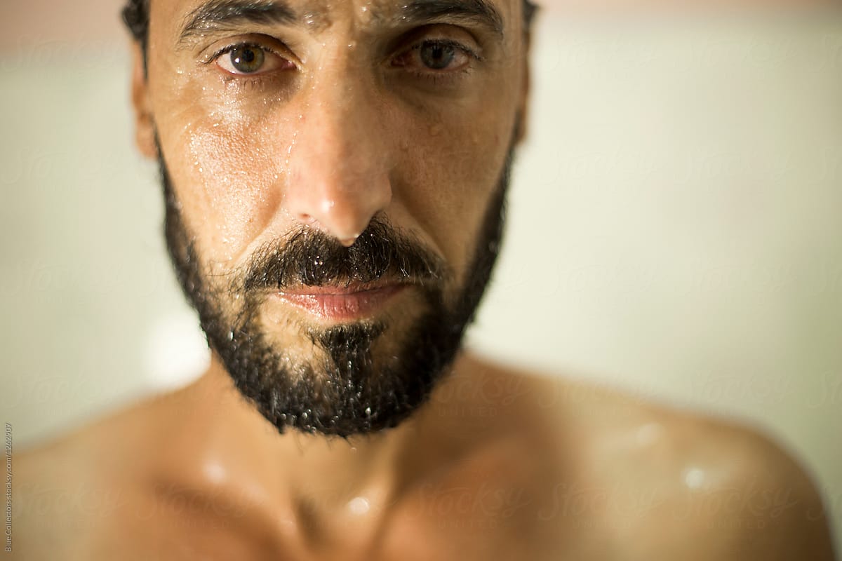 Face of bearded man in shower